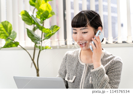電話で通話しながらパソコンを操作する女性秘書 114576534