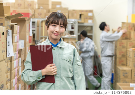 倉庫でバインダーを持つ作業着姿の若い女性 114576892
