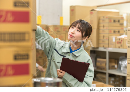 倉庫で検品作業する作業着姿の若い女性 114576895