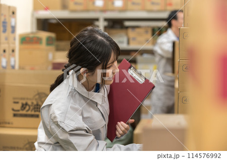 倉庫で検品作業する作業着姿の若い女性 114576992