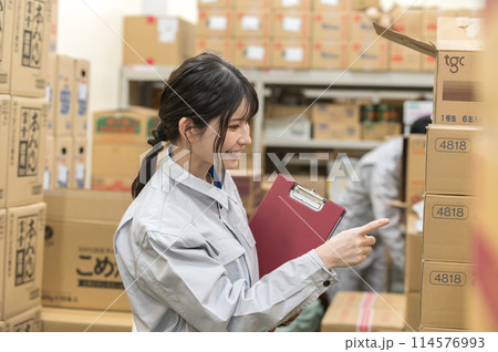 倉庫で検品作業する作業着姿の若い女性 114576993