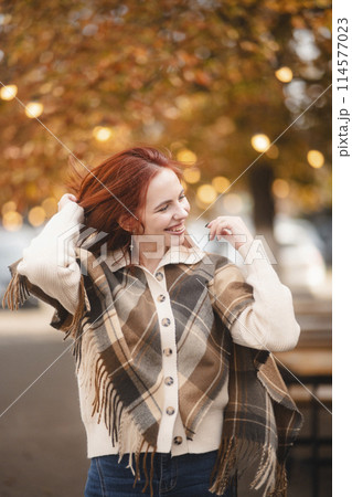 A sunny red-haired woman giggles with glee, infusing the autumn city with joy. A sunny red-haired woman giggles with glee, infusing the autumn city with joy. 114577023