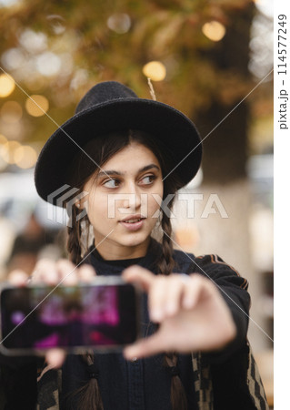 An elegant and stylish lady, accessorized with a black hat and a braided hairstyle. 114577249