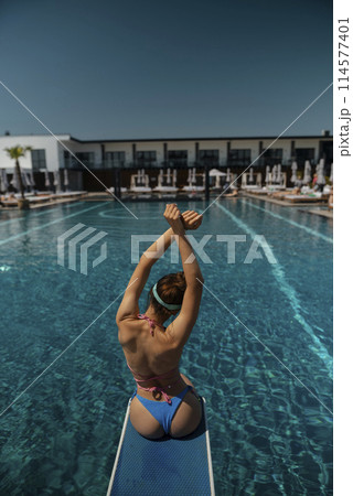 A graceful girl in a bathing suit lounges by the pool, her back to the poolside. A graceful girl in a bathing suit lounges by the pool, her back to the poolside. 114577401