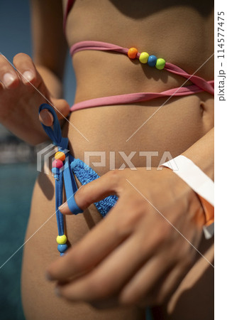 An energetic and vibrant lady enjoys sunbathing in her bikini by the poolside. An energetic and vibrant lady enjoys sunbathing in her bikini by the poolside. 114577475