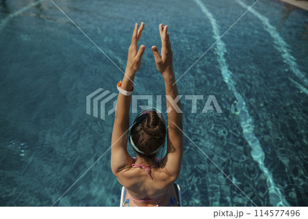 A stunning lady in a bikini reclines by the poolside, her back turned to the water. A stunning lady in a bikini reclines by the poolside, her back turned to the water. 114577496