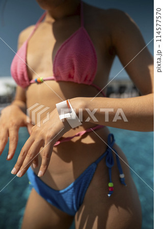 A trendy and sophisticated woman looks stunning in her blue bikini by the poolside. 114577570