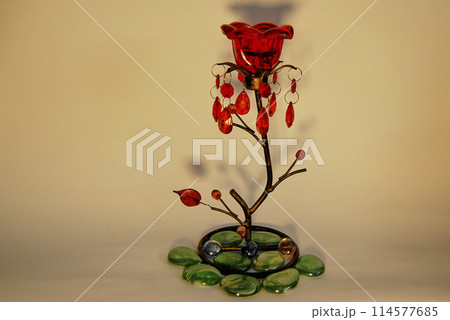 Candlestick in the shape of a flower.With a red bud and decorated with green stones. Candlestick in the shape of a flower.With a red bud and decorated with green stones. 114577685
