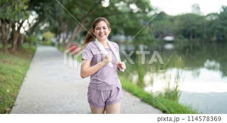 Young asian woman enjoying a morning run in a park. Workout exercise in the morning. Healthy and active lifestyle concept 114578369