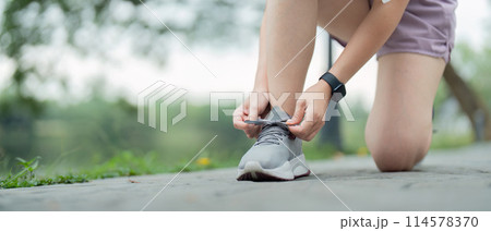 Young woman tying shoelace in the park. Sport and fitness concept 114578370