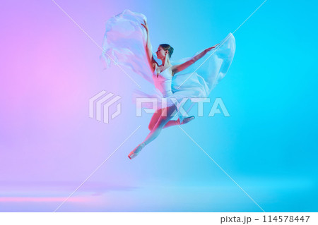 Luminous leap. Ballet dancer in white tutu jumping while dancing in motion in neon light against vivid gradient background. 114578447