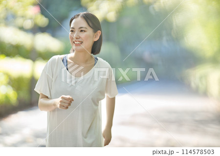 スポーツウエアでランニングをする笑顔の若い女性 114578503