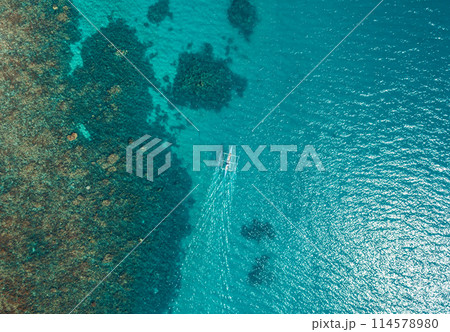 Aerial top view of Banca boat floating in open sea with clear and turquoise water on sunny day . Tropical landscape. Philippines, Palawan. 114578980