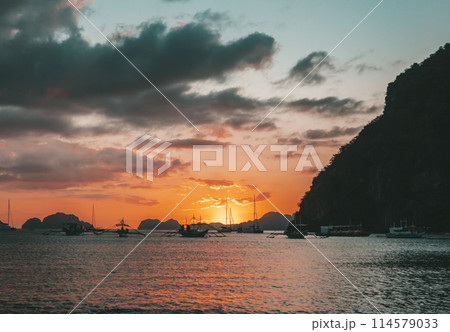 Boats anchored in a calm bay at sunset near scenic islands. Philippines, Palawan. 114579033