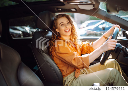 Smiling woman driving a car. Young traveler driving. Car travel, lifestyle concept. 114579631