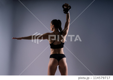Attractive young athlete with muscular body exercising crossfit workout with kettlebell. 114579717