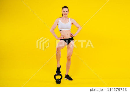 Attractive young athlete with muscular body exercising crossfit workout with kettlebell. 114579738