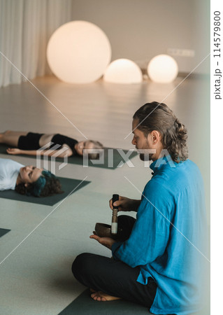 Children relax lying down to the sounds of a Tibetan bowl in the fitness room. Children's yoga Children relax lying down to the sounds of a Tibetan bowl in the fitness room. Children's yoga 114579800