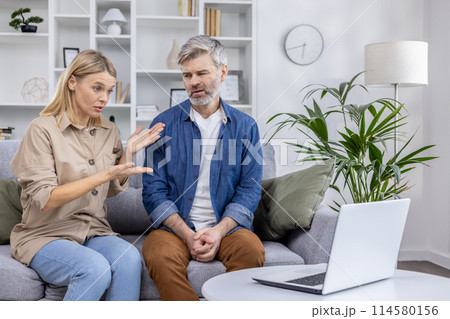 Couple sits on the couch having a video call consultation with a psychologist, discussing family conflict and therapy Couple sits on the couch having a video call consultation with a psychologist, discussing family conflict and therapy 114580156