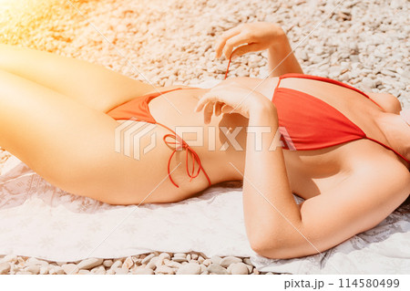 Happy woman taking red bikini off on beach for tan, lady stripping holiday swimsuit with bow in string. Fun, beauty and relax, sexy model untying swimming costume bra, girl in swimwear on vacation 114580499