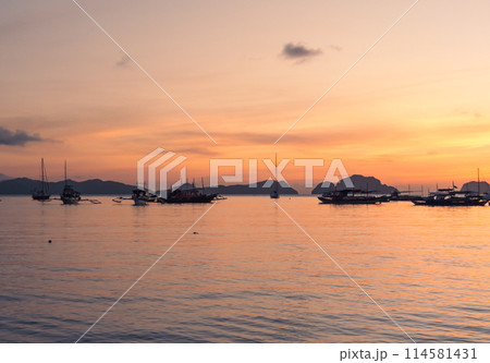 Boats anchored in a calm bay at sunset near scenic islands. Philippines, Palawan. 114581431