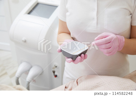 Cosmetologist applying gel before doing laser hair removal epilation on female leg in a salon Cosmetologist applying gel before doing laser hair removal epilation on female leg in a salon 114582248