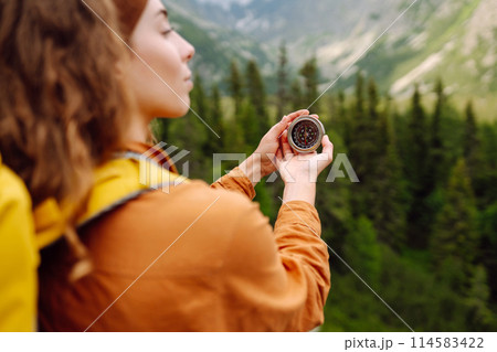Wanderlust concept. Stylish woman holding a compass in her hand while traveling in the mountains. 114583422