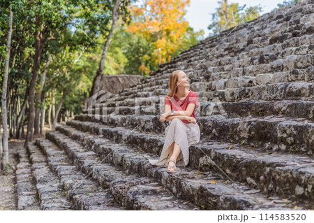 Woman tourist at Coba, Mexico. Ancient mayan city in Mexico. Coba is an archaeological area and a famous landmark of Yucatan Peninsula. Cloudy sky over a pyramid in Mexico 114583520