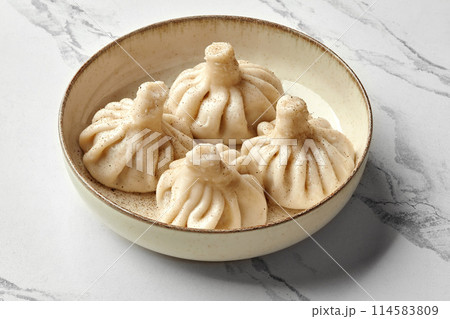 Khinkali dumplings sprinkled with black pepper on ceramic plate Khinkali dumplings sprinkled with black pepper on ceramic plate 114583809