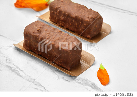Chocolate-glazed cottage cheese bars with nuts on marble with flower petals 114583832