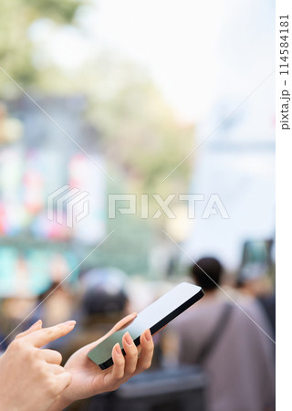 繁華街でスマートフォンを操作する女性の手元 繁華街でスマートフォンを操作する女性の手元 114584181