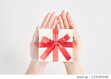 プレゼント用に包装された箱を持つ女性の手元 114584349