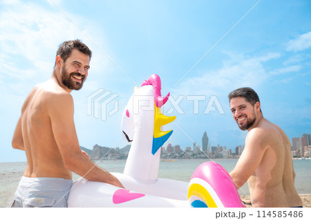 Backside Friends with float on beach smiling happy with sea in background Backside Friends with float on beach smiling happy with sea in background 114585486