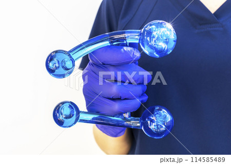 Doctor Holds Blue Acrylic Back, Leg, Neck Massage Tool with Gloved Hand. Deep Tissue Massage, Thumb Massager with Knobs for Gentle Point, Muscles Relaxation. Horizontal 114585489