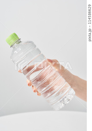 水の入ったペットボトルを持つ女性の手元 水の入ったペットボトルを持つ女性の手元 114586629