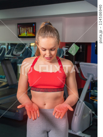 Young woman in sportswear having ache on palms after training in gym 114586940