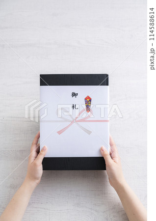 御礼の熨斗がかかった贈り物を渡す女性の手 114588614
