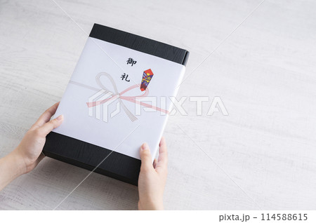 御礼の熨斗がかかった贈り物を渡す女性の手 御礼の熨斗がかかった贈り物を渡す女性の手 114588615