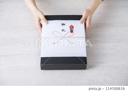 御礼の熨斗がかかった贈り物を渡す女性の手 114588616