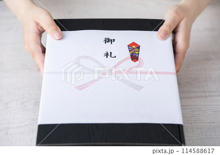 御礼の熨斗がかかった贈り物を渡す女性の手 114588617