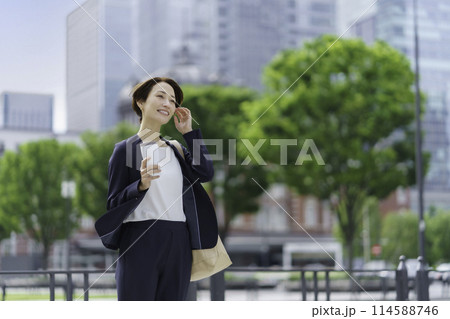 タンブラーを手に持ってオフィス街に立つビジネスウーマン 114588746