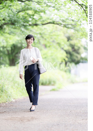 新緑の道を歩く若いビジネスウーマン 新緑の道を歩く若いビジネスウーマン 114588905