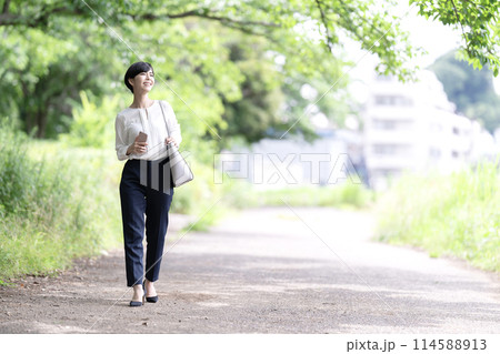 新緑の道を歩く若いビジネスウーマン 新緑の道を歩く若いビジネスウーマン 114588913