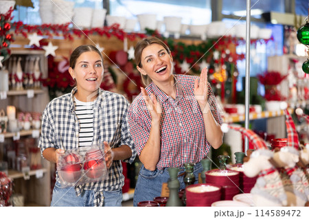 Two female friends in store are choosing Christmas decorations for celebrating Christmas. 114589472