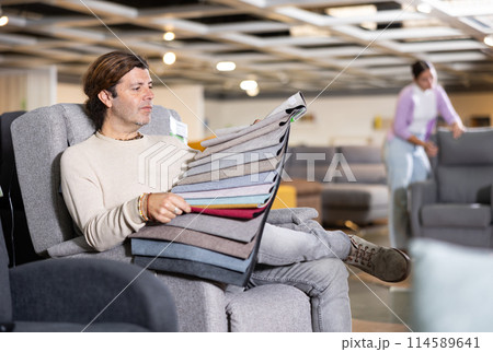 Man choosing material for sofa in furniture showroom Man choosing material for sofa in furniture showroom 114589641