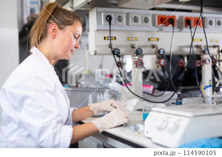 Female pharmacist researcher waiting for color change in test tube while conducting experiment in laboratory 114590105