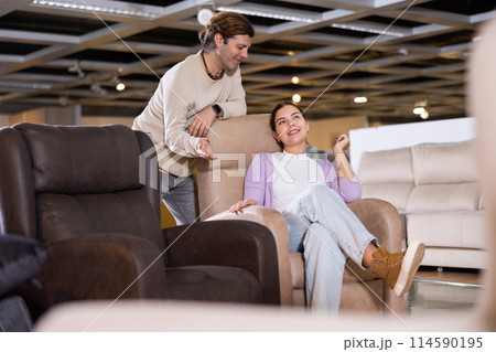 Man and woman sitting around in armchairs in furniture store Man and woman sitting around in armchairs in furniture store 114590195