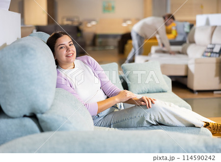 Woman deciding on buying a sofa in furniture shop 114590242