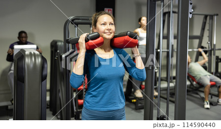 Young woman is engaged on simulator to strengthen muscles of legs in gym Young woman is engaged on simulator to strengthen muscles of legs in gym 114590440
