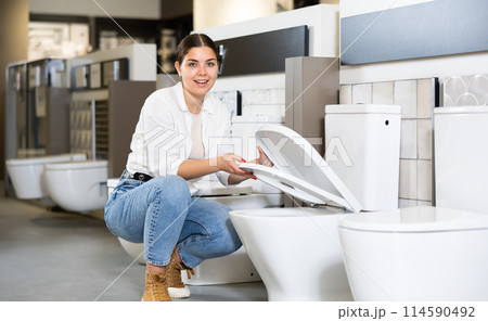 in plumbing department, female buyer checks for defects of toilet before purchasing toilet pan in plumbing department, female buyer checks for defects of toilet before purchasing toilet pan 114590492